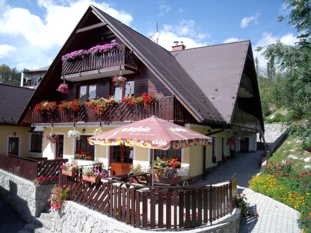 Vysoke Tatry - Tatranska Lesna里斯拉旅馆的一座房子,里面摆放着遮阳伞和椅子,鲜花盛开