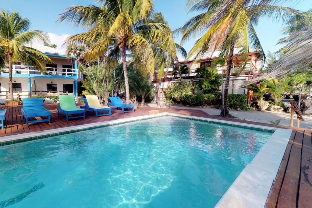 珀拉什奇亚Condo #31 @ Beachside Villas的游泳池拥有蓝色和绿色的椅子和棕榈树