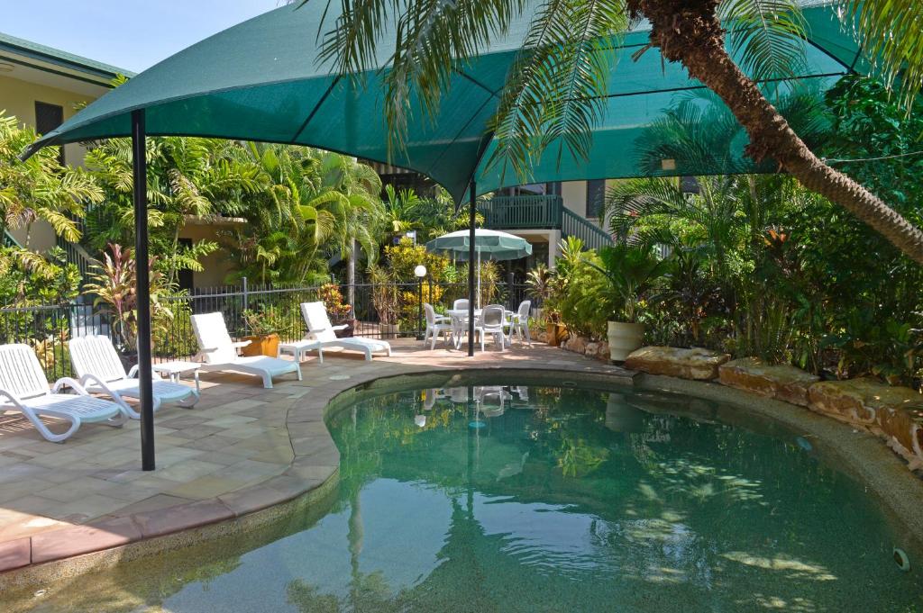 达尔文城市花园公寓 的一个带遮阳伞和椅子的游泳池以及庭院