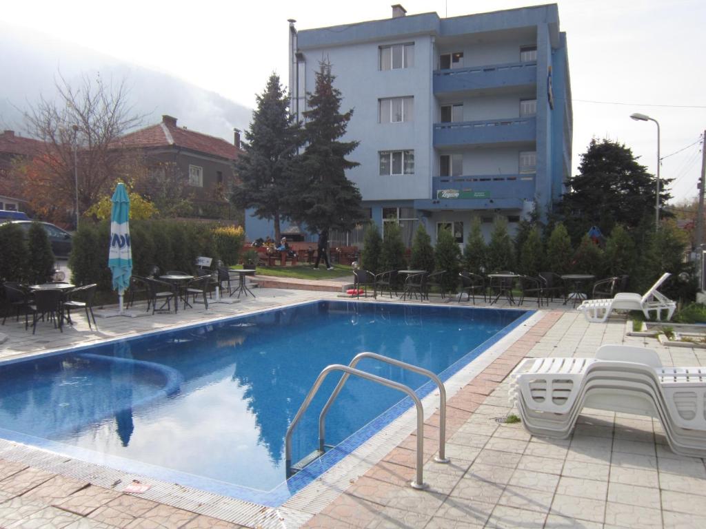 萨帕雷瓦巴尼亚日耳曼酒店的一座带桌椅的游泳池以及一座建筑