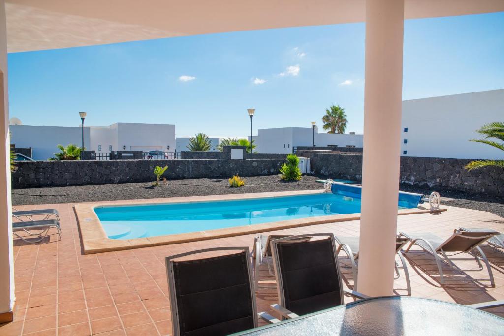 普拉亚布兰卡Villas Blancas的庭院设有游泳池、桌子和椅子。