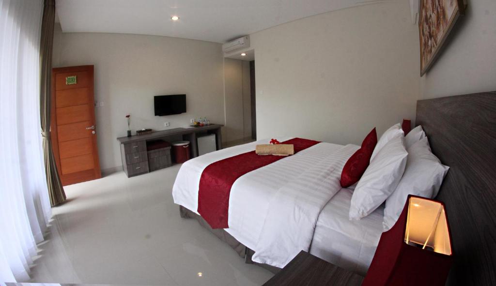 沙努尔普里凯萨里旅馆的卧室配有带红色枕头的大型白色床