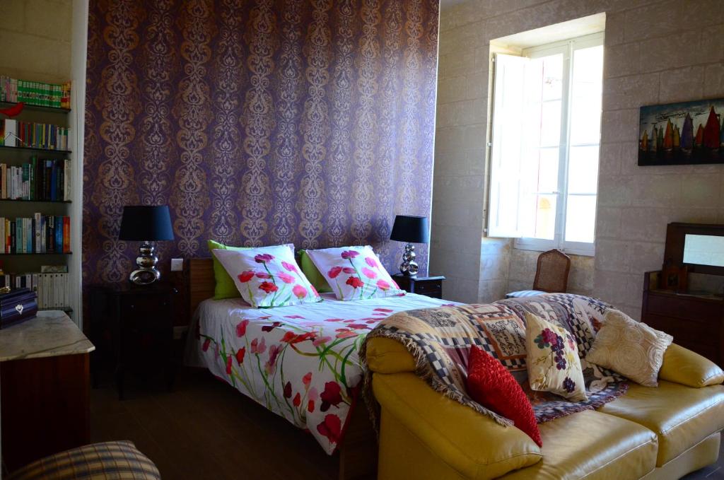 Żejtun巴拉自奥1787公寓的一间卧室配有一张床、一张沙发和一个窗口