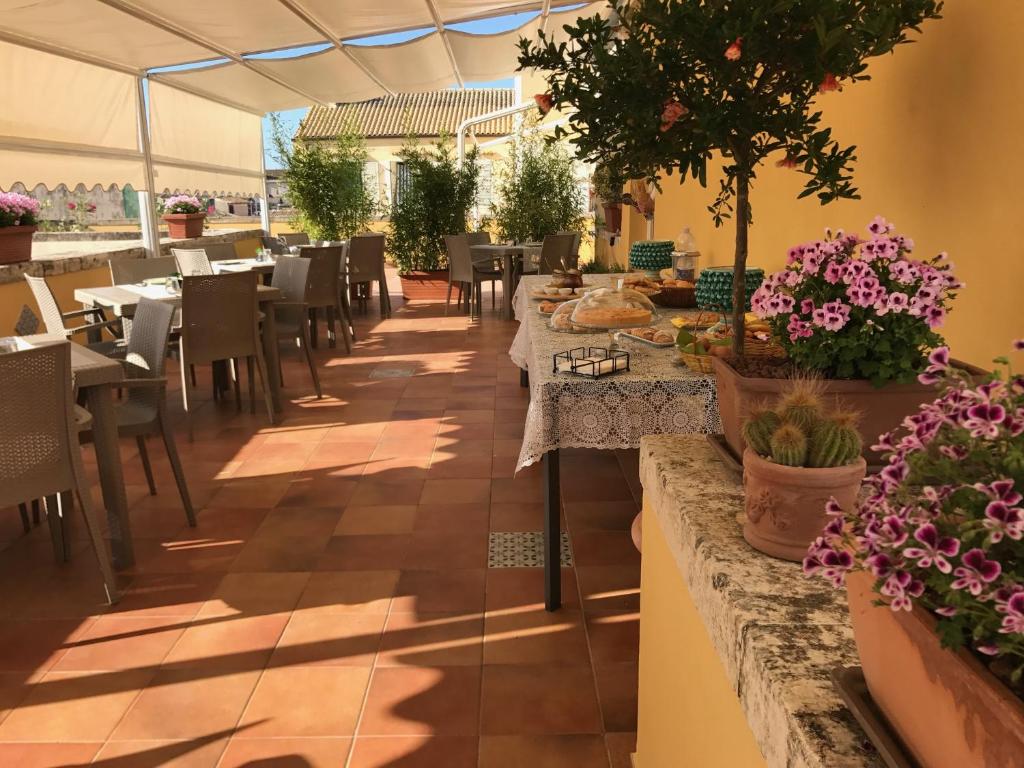 锡拉库扎艾桑提克罗那提酒店的一间设有桌椅和盆栽的餐厅