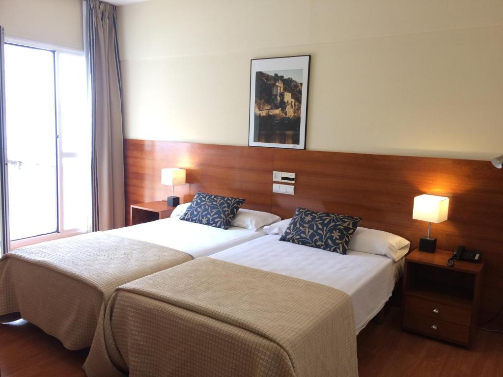 索里亚Hotel Alda Ciudad de Soria的酒店客房设有两张床和两盏灯。