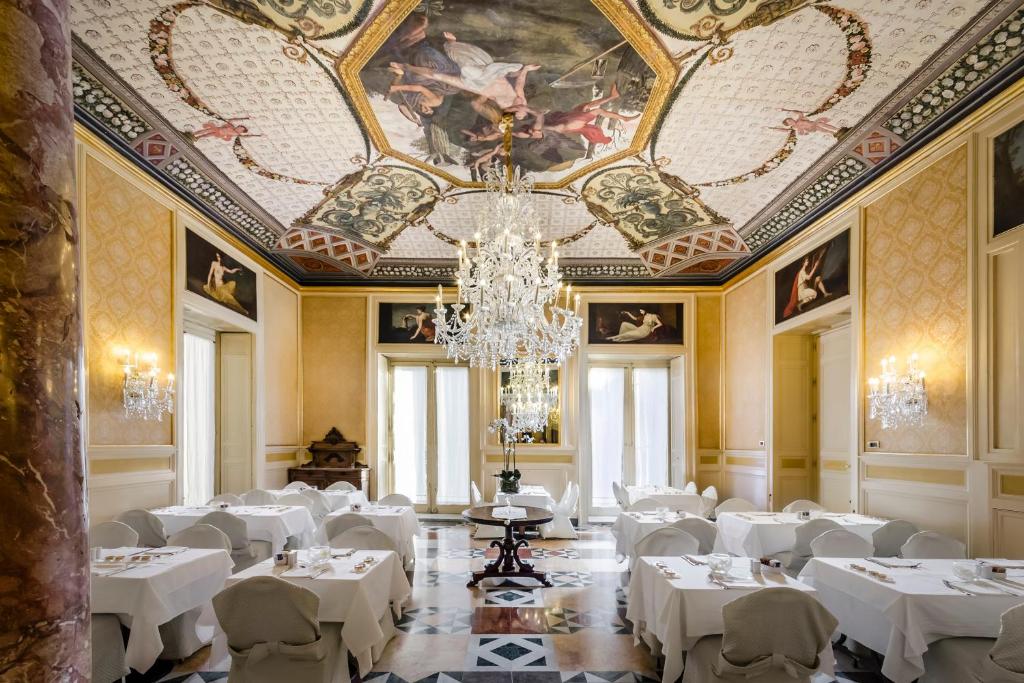 巴勒莫欧洲之星中央皇宫酒店的一间设有白色桌子和吊灯的天花板的用餐室