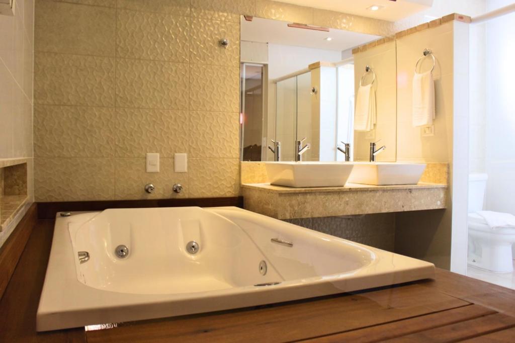 瓜鲁雅Don Marco's Hotel com Restaurante e Pizzaria的大型浴室设有大浴缸和水槽
