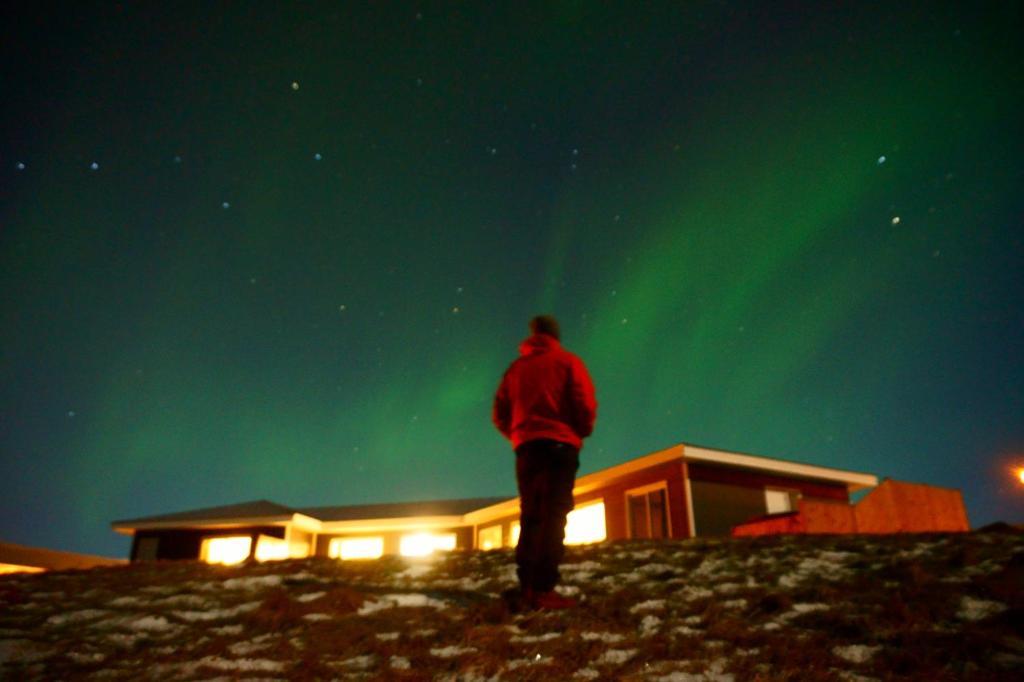 华姆斯唐吉Guesthouse 46的站在山丘上,看着北极光的人