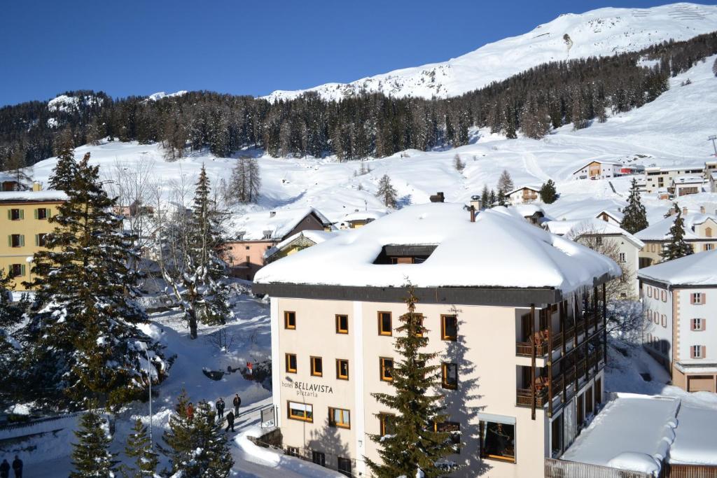 弗坦Hotel Bellavista Ftan的一座雪地中的建筑,背景是一座山