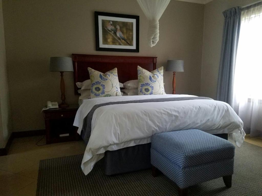 利隆圭Ufulu Gardens Hotel的一间卧室配有一张大床和蓝色的搁脚凳