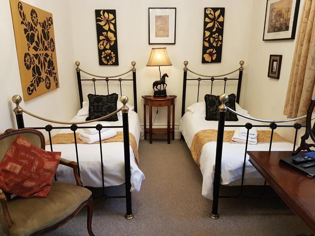 东格林斯特德哥特式酒店的一间卧室配有两张床、一把椅子和一张书桌