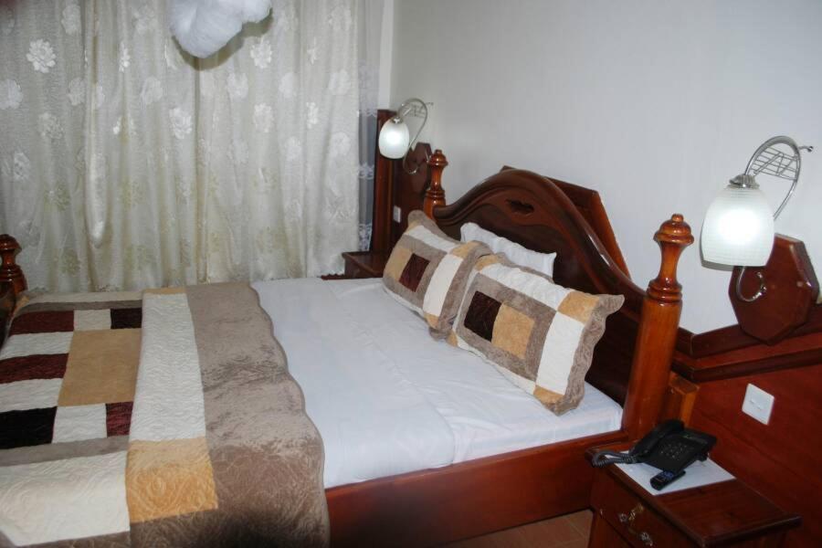 姆巴拉拉Palm world Hotels Mbarara的一间卧室配有一张带枕头的木床