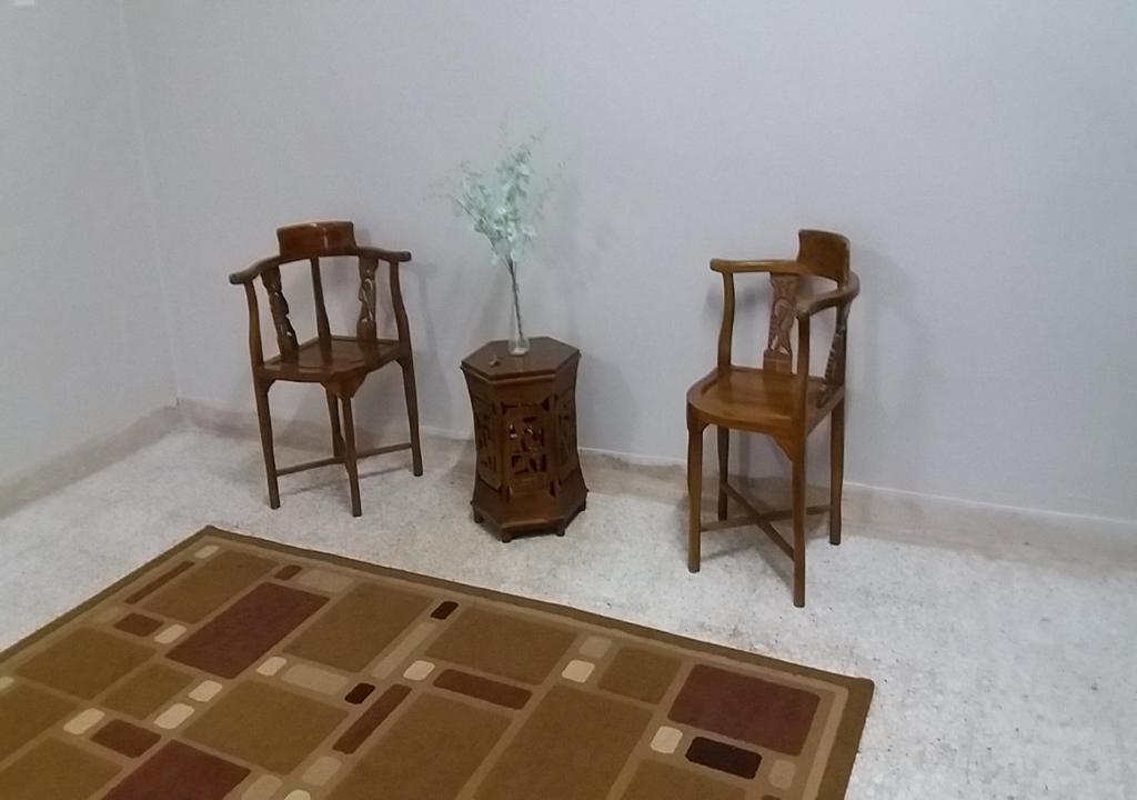 马六甲巴图贝伦丹度假屋的一间设有两把椅子和一张带花瓶的桌子的房间