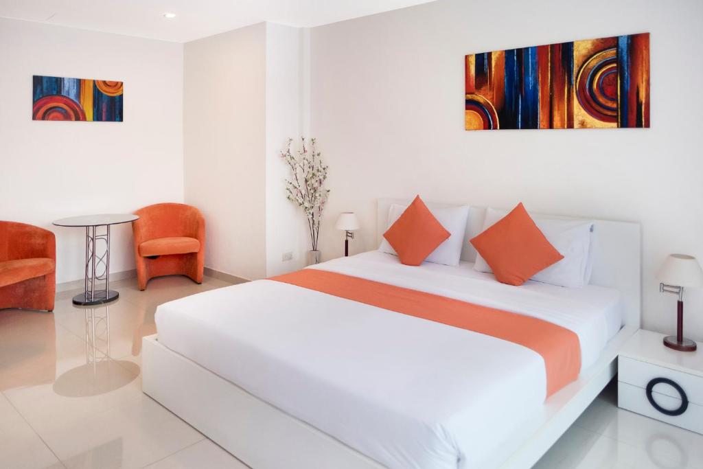 乔木提恩海滩阳光海滩酒店的白色卧室配有带橙色枕头的大床