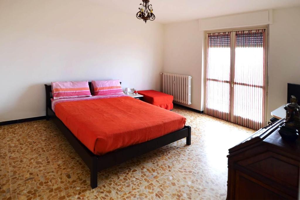 贝内瓦吉恩纳Bene Vagienna Holiday House的一间卧室配有一张带红色床单的床和一扇窗户。