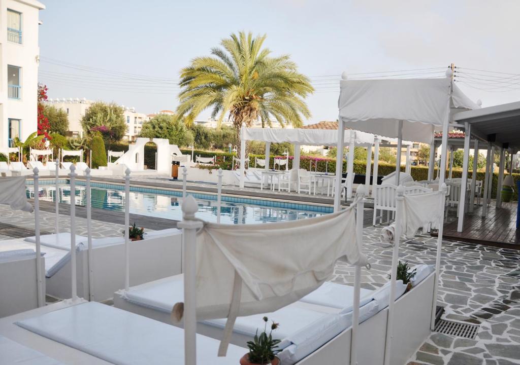 帕福斯Tasmaria Aparthotel的一个带游泳池、白色椅子和一个游泳池的度假胜地