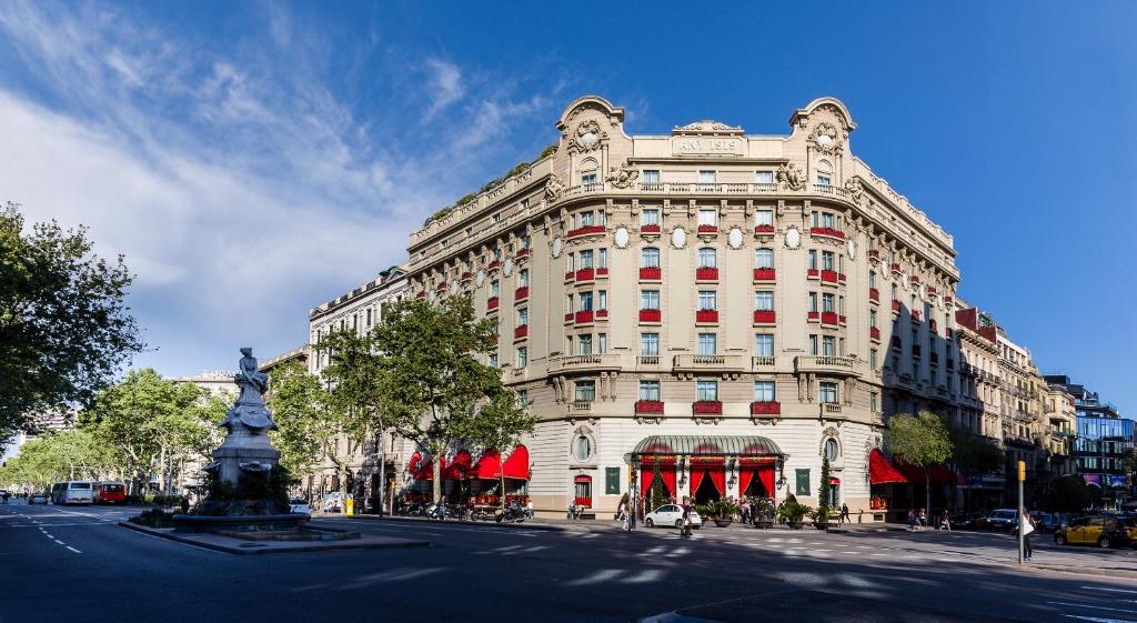 巴塞罗那Hotel El Palace Barcelona的一座白色的大建筑,前面有雕像