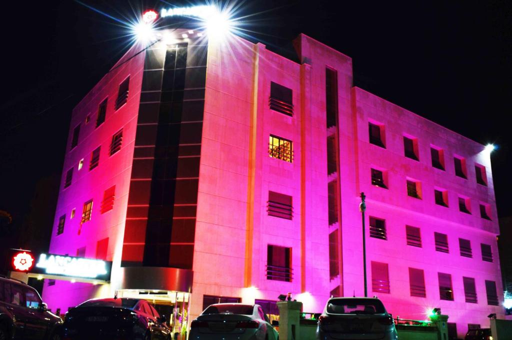 安曼兰开斯特公寓花园酒店的一座建筑物晚上点亮粉红色