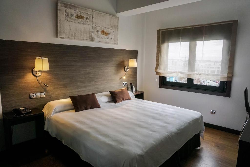 拉科鲁尼亚Suites Coruña的卧室设有一张白色大床和一扇窗户。