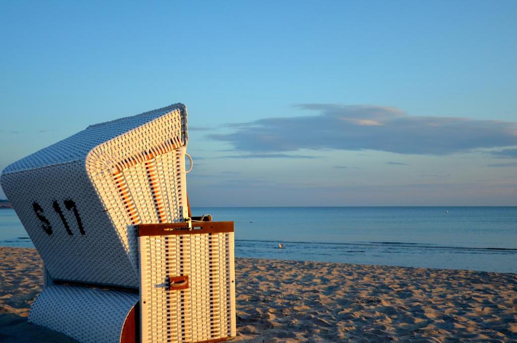 博尔滕哈根Strandvilla Waldhaus的沙滩上的藤椅和手提箱