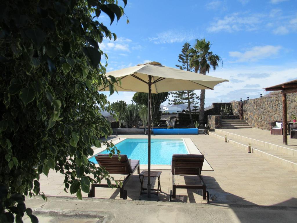 蒂亚斯El Cercado的游泳池配有遮阳伞和两把椅子,桌子配有遮阳伞