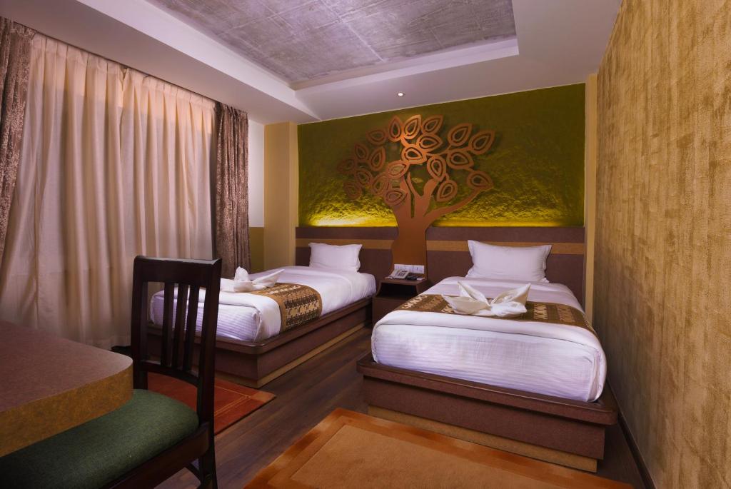 加德满都菩提精品酒店的墙上有一棵树,房间内设有两张床