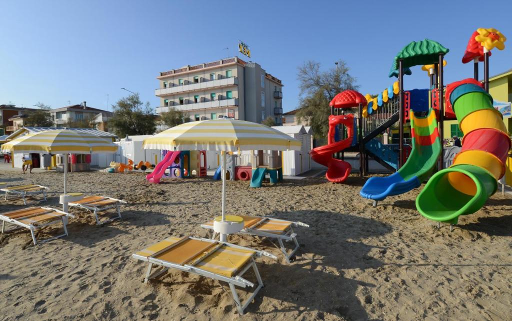 西尼加利亚Hotel Rex的海滩上带椅子和遮阳伞的游乐场