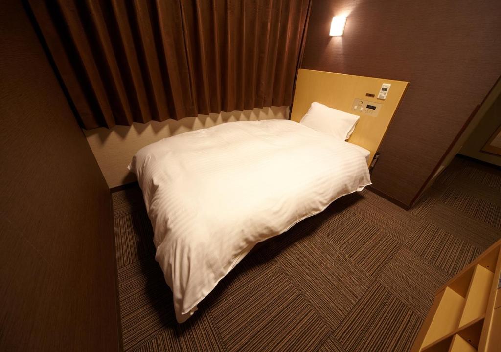 广岛多美迎广岛酒店的小房间一张大白色的床