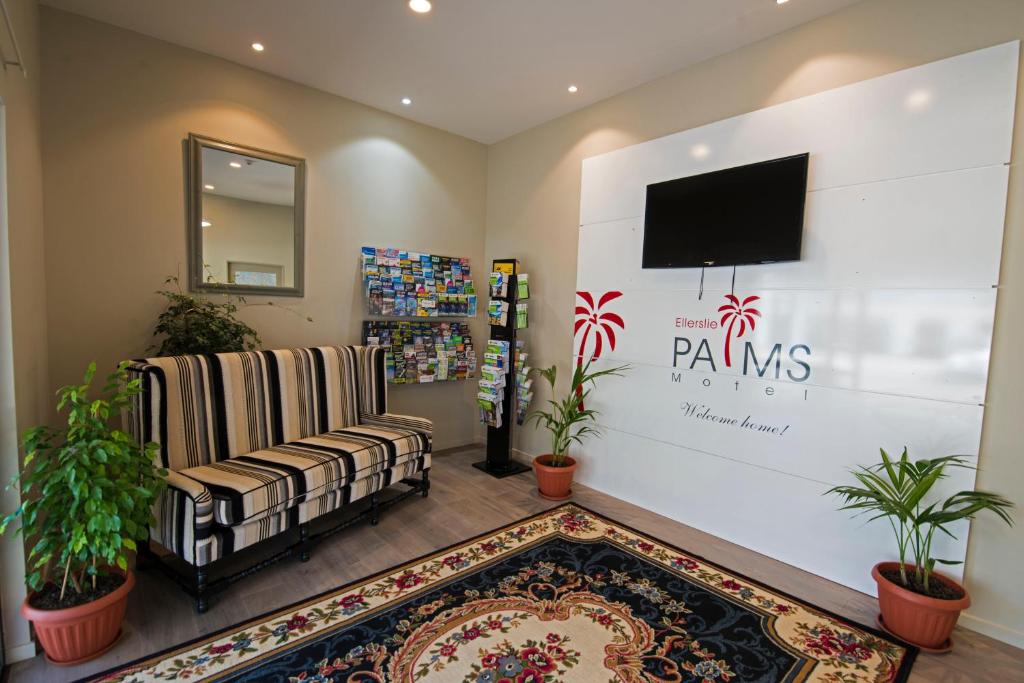 奥克兰艾勒斯利棕榈汽车旅馆的客厅配有电视、沙发和地毯。