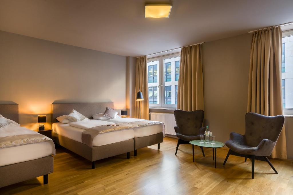 美因河畔法兰克福Munique Hotel Frankfurt City的酒店客房带两张床和一张桌子以及椅子。