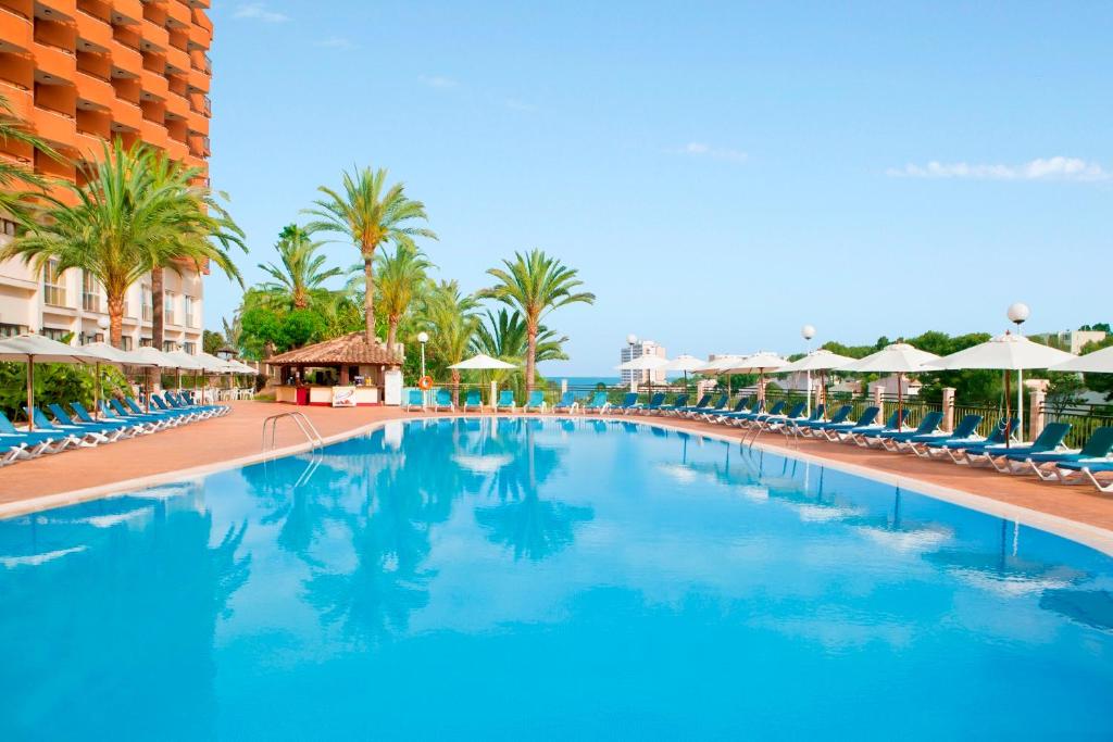 卡拉斯马略卡HSM Canarios Park的棕榈树和椅子的度假村的游泳池