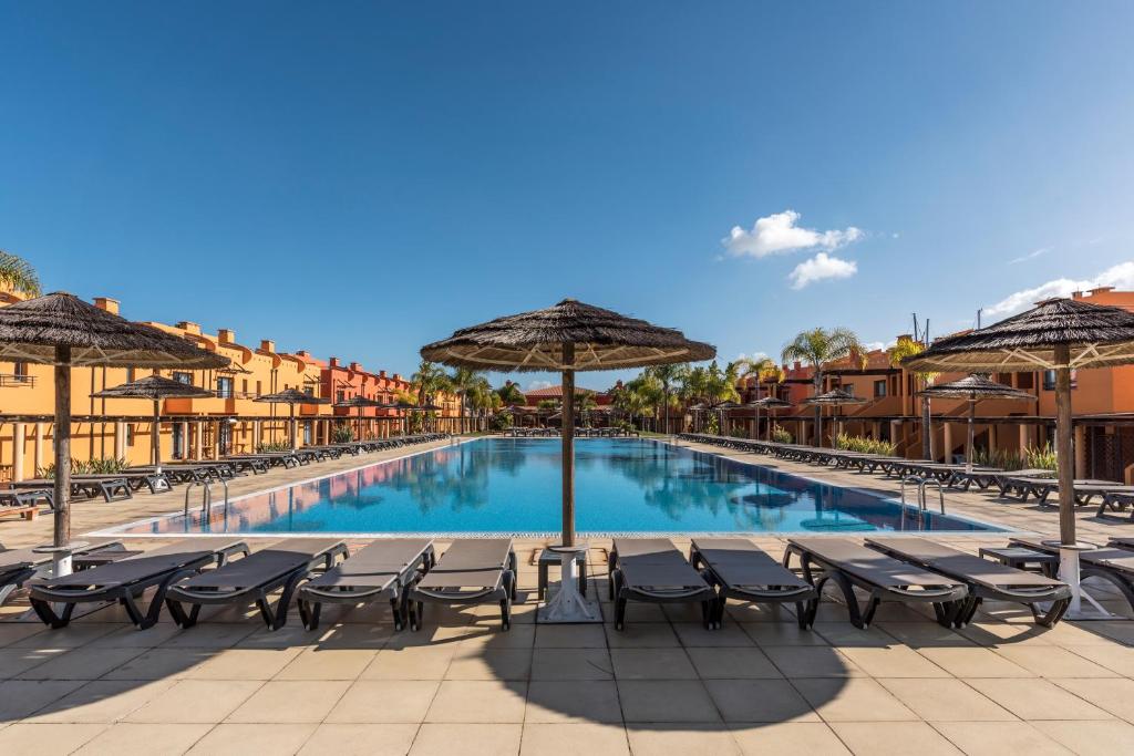 波尔蒂芒Luxury Apartment, Marina, Beach & Pool的度假村前方的带椅子和遮阳伞的游泳池