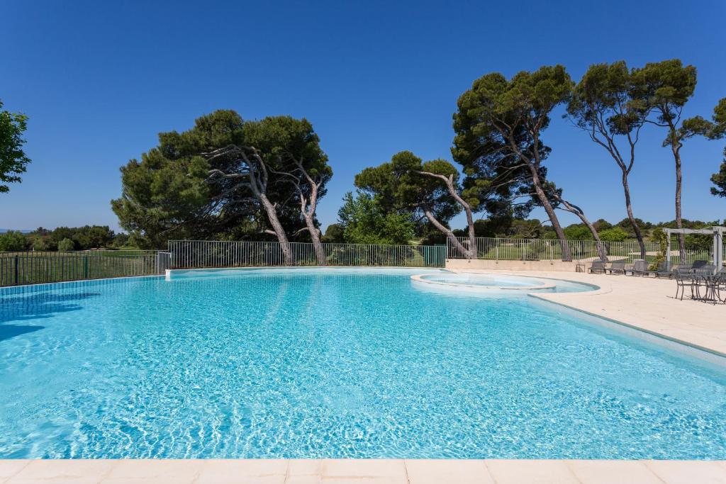 索马讷-德沃克吕兹Madame Vacances Domaine du Provence Country Club Service Premium的拥有蓝色海水和树木的游泳池