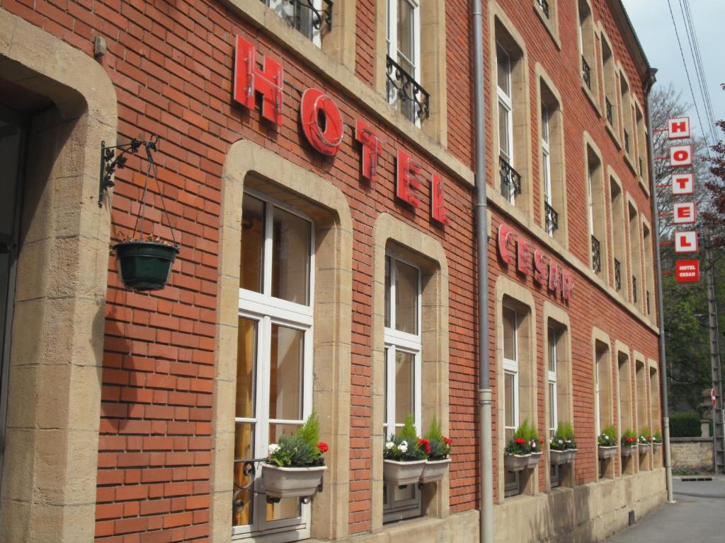 沙勒维尔-梅济耶尔塞萨尔酒店的一座红砖建筑,里面装有窗户和植物