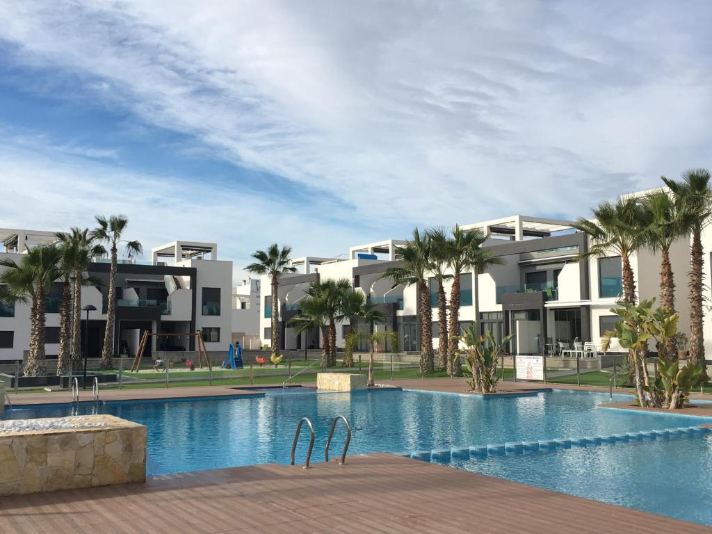 奥里韦拉海滩Casa de la vida La Zenia的棕榈树和建筑的度假游泳池