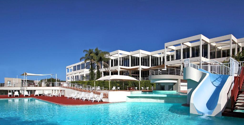 科夫斯港海滨奥珀尔卡芙度假酒店的大楼前带水滑梯的游泳池