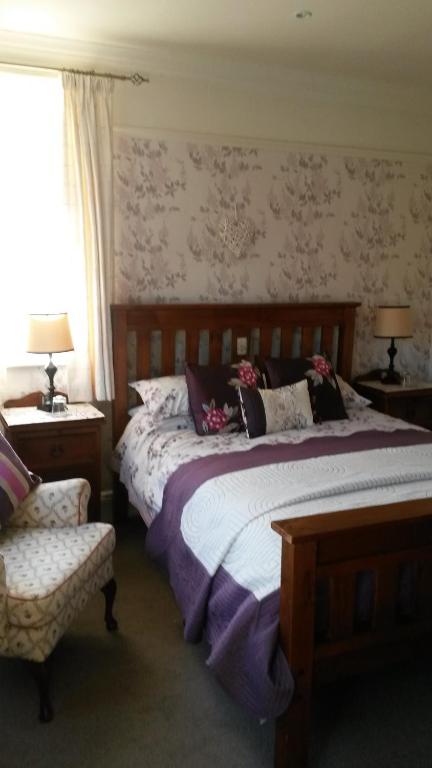 谢林汉姆Ashbourne House的一间卧室配有一张大床和一把椅子