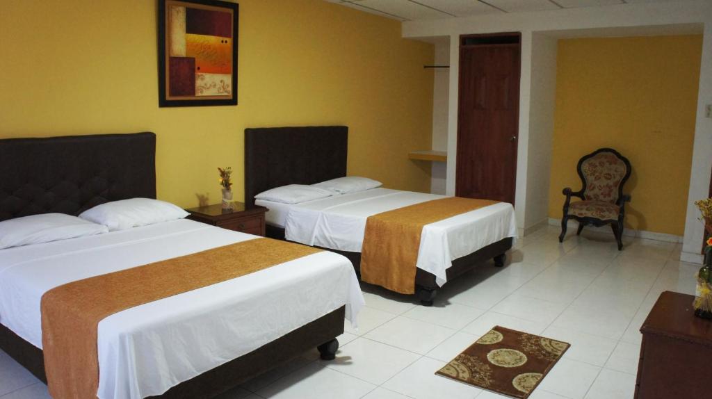 卡利Hotel Parque del Perro的酒店客房,配有两张床和椅子