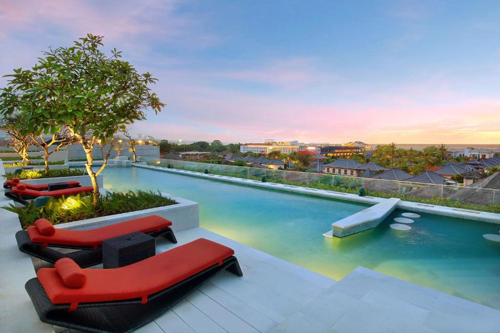 库塔巴厘岛大使酒店的一座带红色家具的游泳池
