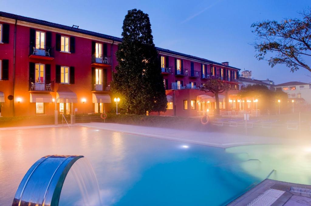 西尔米奥奈芳提波伊欧拉酒店的一座游泳池,在晚上在建筑物前