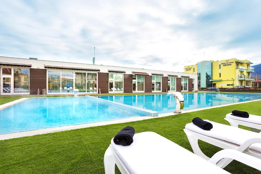 道那班亚Complex Europe的一座带白色椅子的游泳池和一座建筑