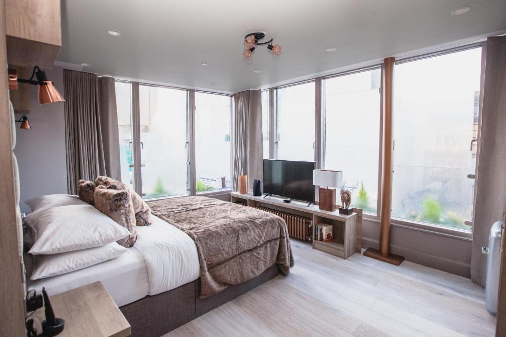 都柏林克拉伦登套房酒店的一间卧室设有一张床、一台电视和大窗户