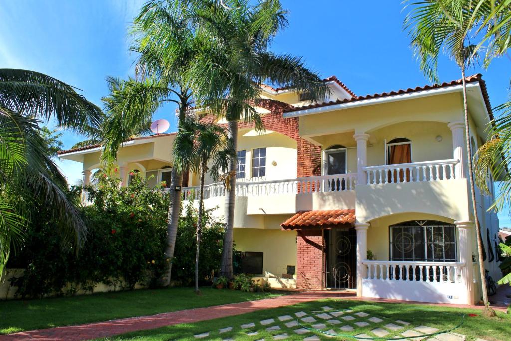 蓬塔卡纳Sweet Home Punta Cana Guest House - VILLA Q15A的前面有棕榈树的房子