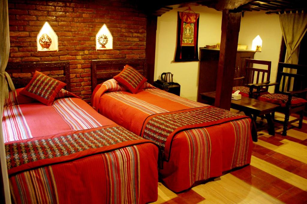 加德满都府庙乡村别墅的一间卧室设有两张床和砖墙