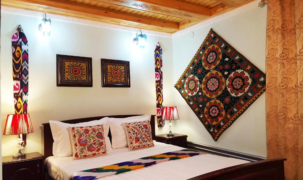 撒马尔罕Jahongir Guest House的一间卧室配有一张带枕头的床,墙上挂有绘画作品