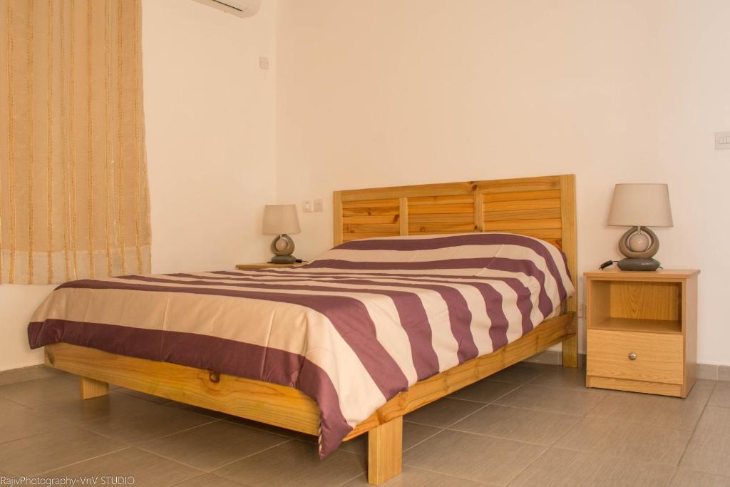 特鲁欧克比赫斯Villa Alexis - Location de vacances à Trou aux Biches的一间卧室配有木床和2个床头柜