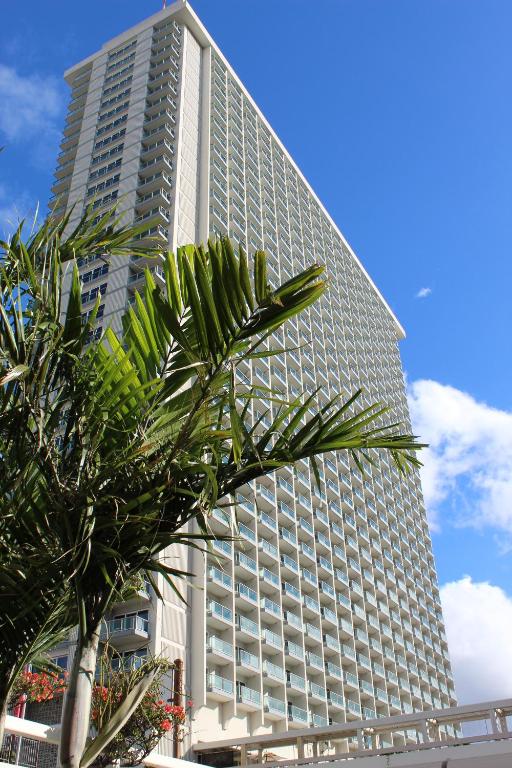 檀香山阿拉莫阿纳LSI度假酒店的一座高大的建筑,前面有一棵棕榈树