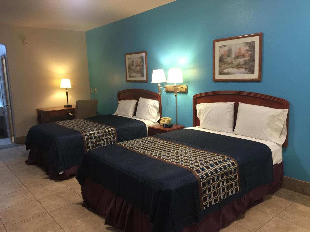 爱丁堡Texas Inn and Suites City Center at University Dr.的两张位于酒店客房的床,拥有蓝色的墙壁