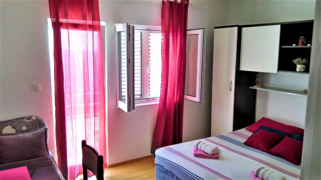 米欧纳Apartment Vesna的一间卧室配有粉红色窗帘、一张床和椅子