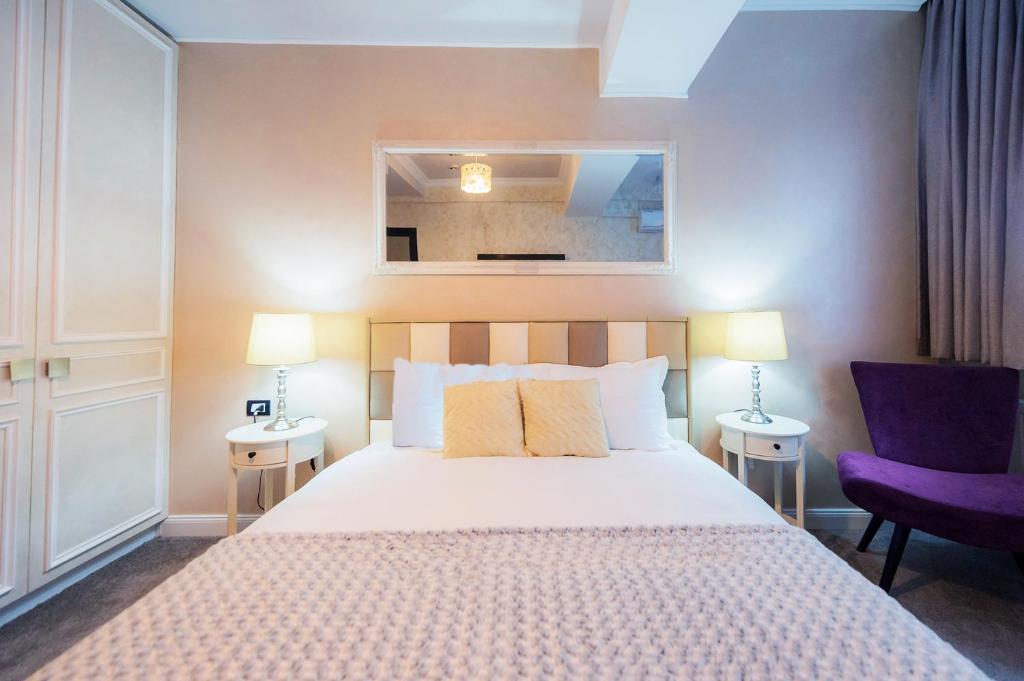 布加勒斯特Brater Luxury的一间卧室配有床和两张桌子及椅子